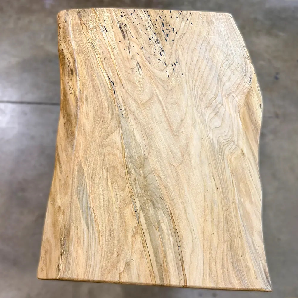 Light live edge spalted maple coffee table with natural edges and spots, on a concrete floor.