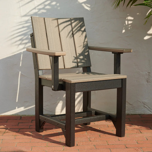 Urban Arm Chair with wide slats and arms on red brick patio, partly shaded by foliage.