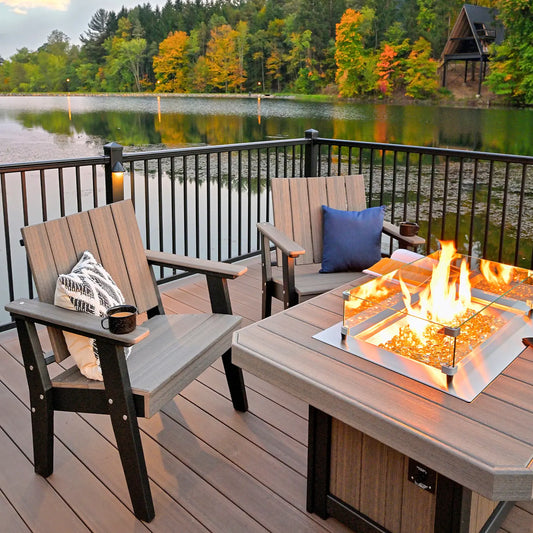 Chairs by a fire pit on a deck, with fall lake views and cozy touches like a cup and pillow.