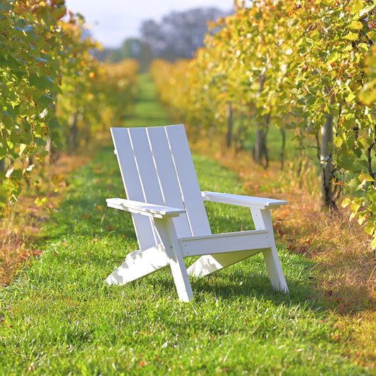 White Adirondack chair on grass between vineyard rows under sunny skies, stylish and durable.