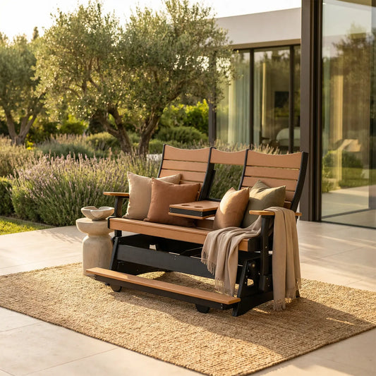 Wood-look glider bench with beige cushions on a patio, greenery and glass house in background.