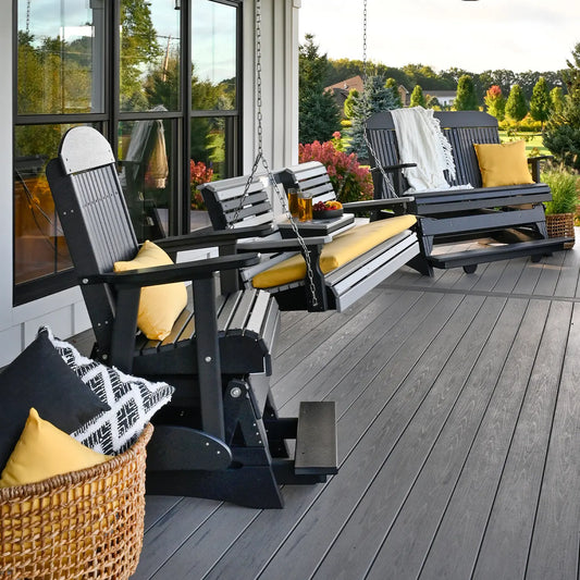 Cozy porch with black and yellow glider chairs, swing bench, pillows, and greenery backdrop.
