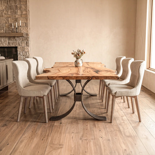 Large maple table with 8 chairs, wood floors, stone fireplace, and dried flowers centerpiece.