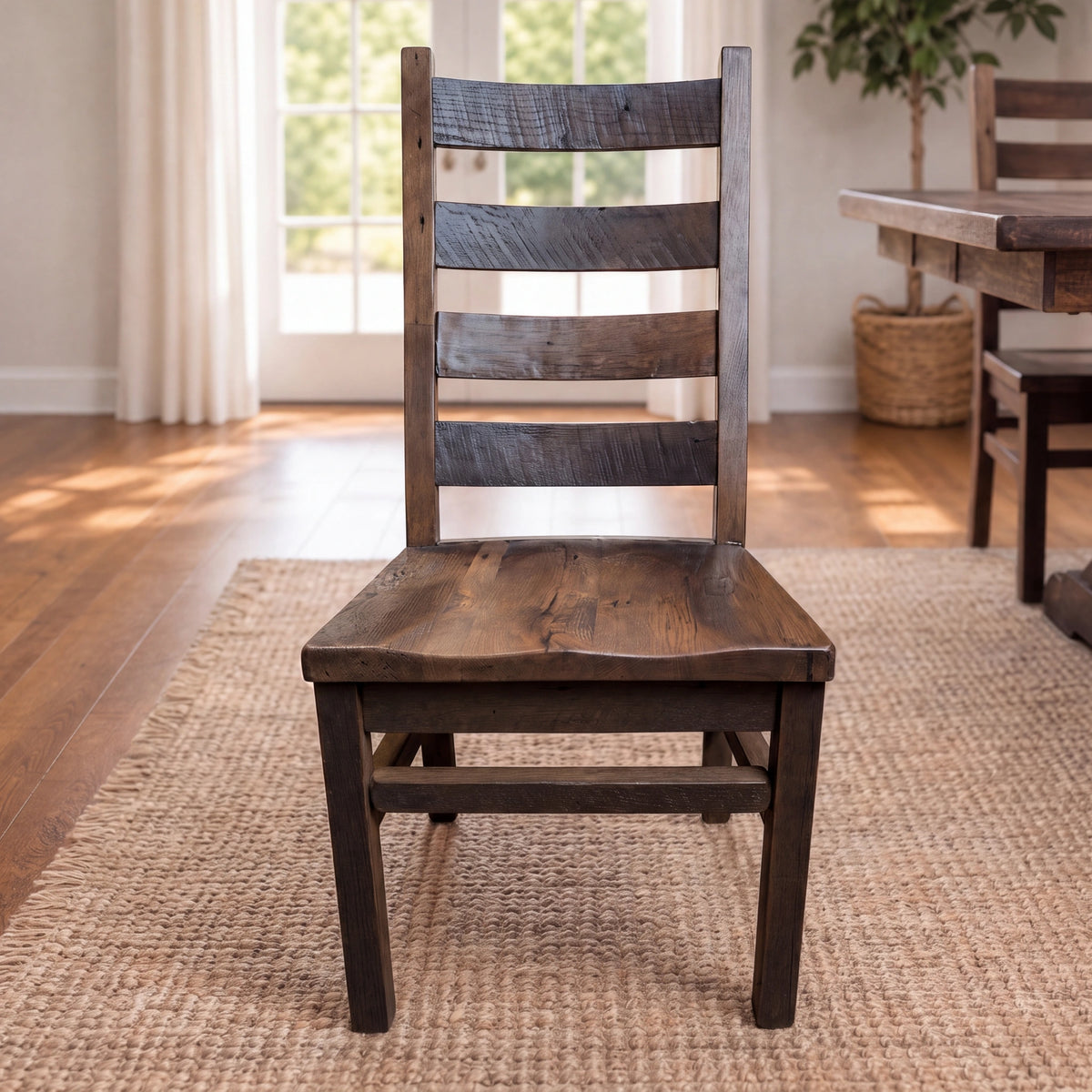 Akron ladder-back dining chair on woven rug in sunny room with hardwood floors and large windows.