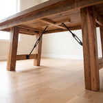 Close-up of Montana table’s underside with sturdy legs, metal braces on light wood floor.