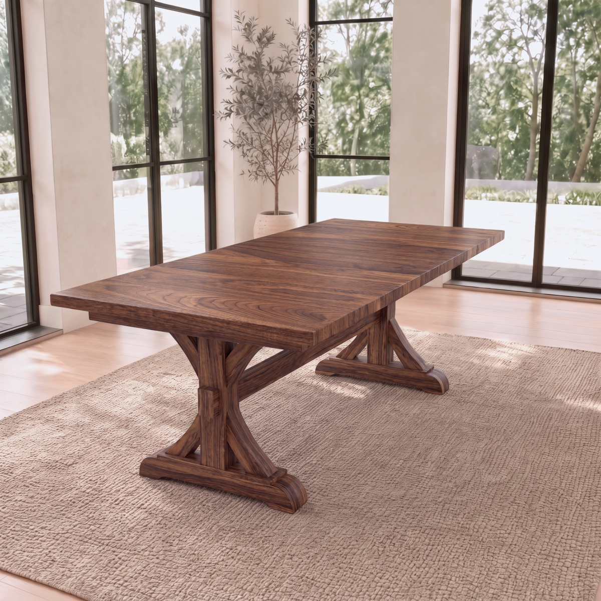 Solid wood dining table with ornate legs on a beige rug in a sunny room with large windows.