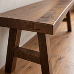 Rustic barnwood bench with a thick, textured seat and splayed legs.