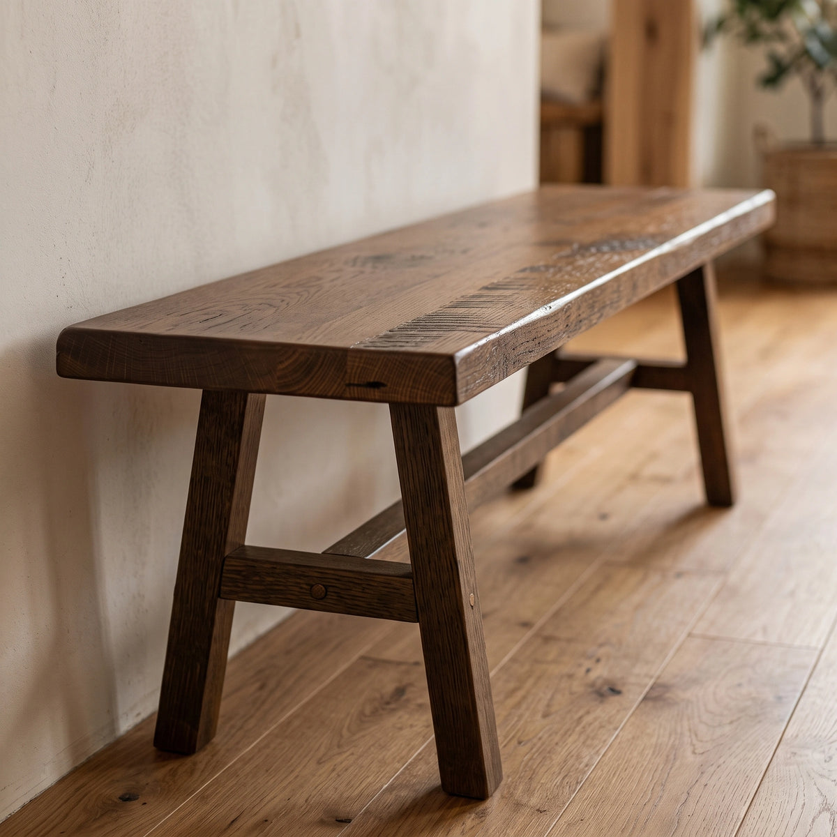 Handcrafted rustic barnwood bench with angled legs and support beam against a wall.