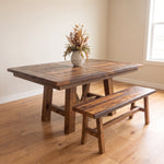 Rustic wood dining table and matching Barnwood bench with a vase of dried flowers.