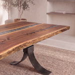 96″ live edge walnut table with metal inlays on black base, on beige rug in modern room.