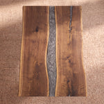 96″ live edge walnut dining table with gray epoxy resin center sits on a textured beige carpet.