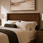 King bed with white bedding, wood headboard, brown pillow; cozy room with lamps and art.
