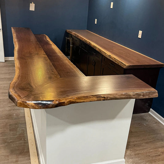 Walnut bar with live edge counter, matching back, blue wall, and light floor.
