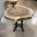 Walnut end table with live edge top, visible rings, steel base on polished concrete floor.