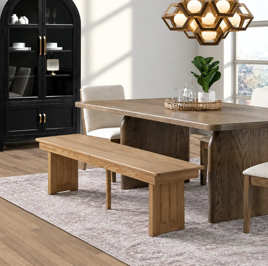 Modern dining room with wood table, bench, chairs, black cabinet, chandelier, and sunlight.