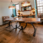 Wooden dining table with metal legs in a room with large windows and decorative lamps.