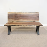 Live edge wood bench with black metal legs on light carpet, set against a white wall.
