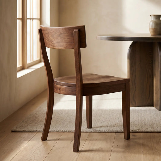Mid-century oak chair by round table and vase on a rug, sunlight streaming through window.