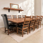 Rustic square dining table with 10 chairs, beige rug, wall shelf, mirror, and soft sunlight.