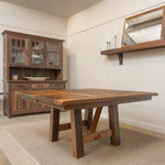 Square oak dining table with hutch, candles, and mirror on beige rug in cozy room.