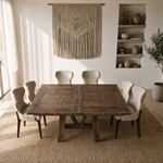 Dining set on rug, pottery shelves, macramé wall art; sunlight from left in neutral room.