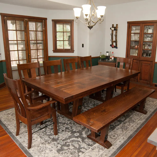 Rustic dining room with cherry wood table, bench, chairs, chandelier, and patterned rug.