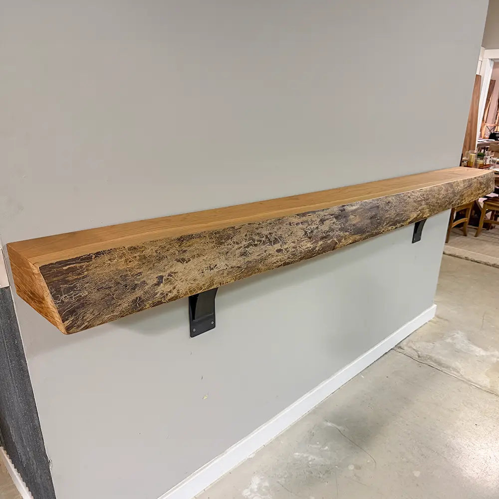 Long live edge cherry wood mantel with glossy finish on gray wall, above light floor and modern decor.