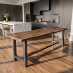 Modern kitchen with wood floors, walnut counter table, and a marble island with two chairs.