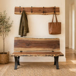 Cozy entryway with live edge bench, coat rack, green jacket, tote, rug, and wood floors.