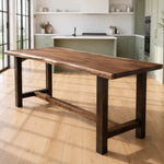 Live edge walnut counter table in sunlit modern kitchen with green cabinets and white counters.