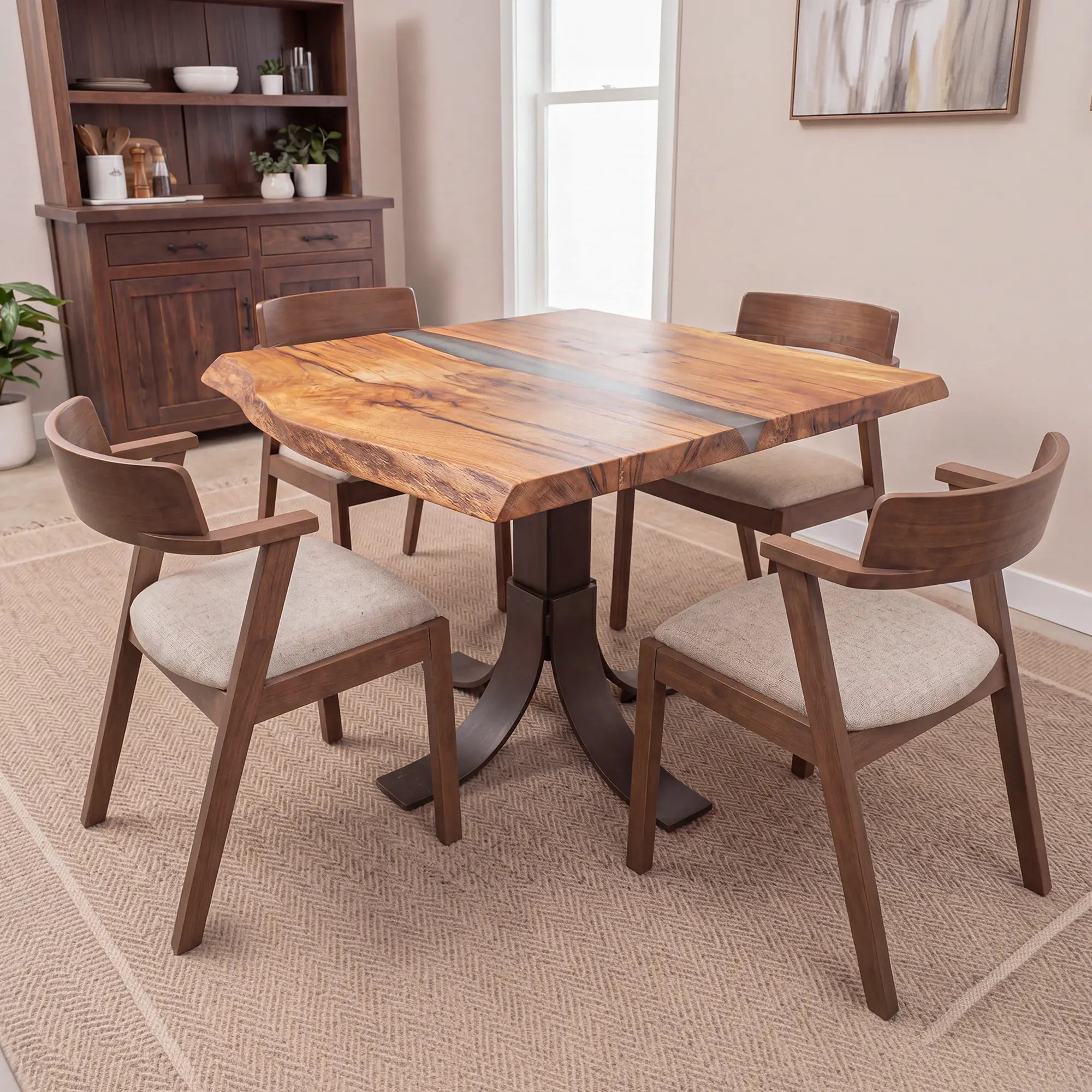 Live edge oak cafe table with chairs on beige rug in bright dining room, art and cabinet behind.