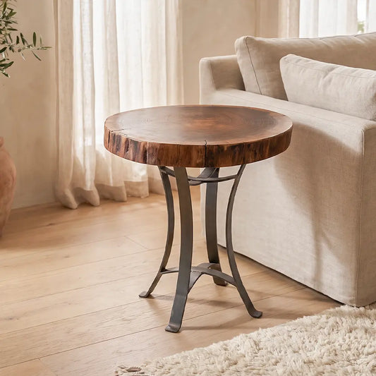 Walnut slab end table with steel base beside beige sofa on light wood floor in cozy room.