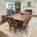 Pathway Dining Table with short plank top and wooden chairs on a rug.