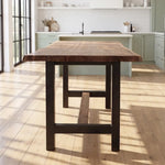 Walnut counter table with steel base in a bright kitchen with sage cabinets and large windows.