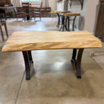 Spalted maple live edge coffee table with black metal legs on concrete floor in showroom.