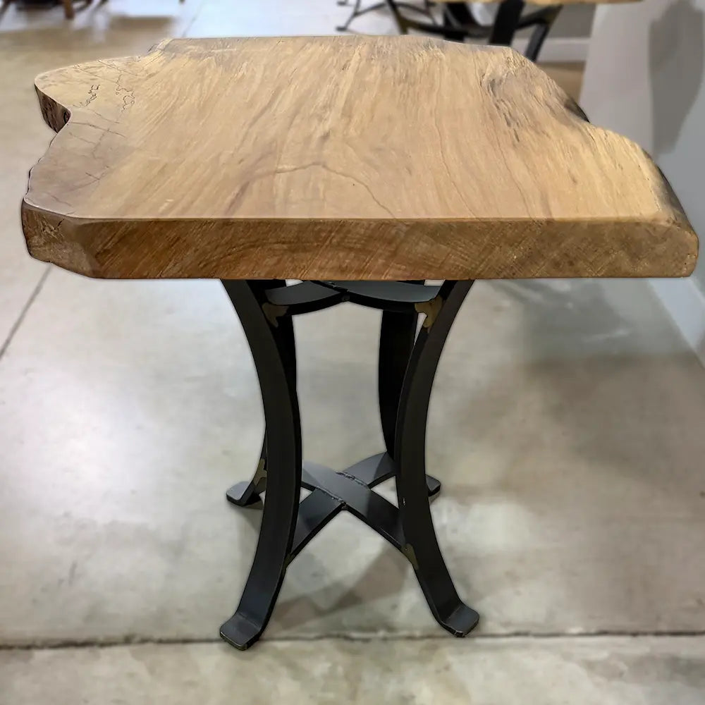 Live edge sycamore end table with black legs on a concrete floor in an indoor setting.