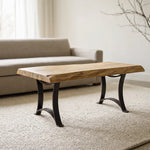 Live edge maple coffee table on beige rug, in front of gray sofa and window in a minimalist room.
