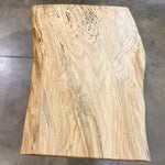 Light live edge spalted maple coffee table with natural edges and spots, on a concrete floor.