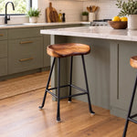 Molded wood tractor seat counter stool with a black steel base in a kitchen.